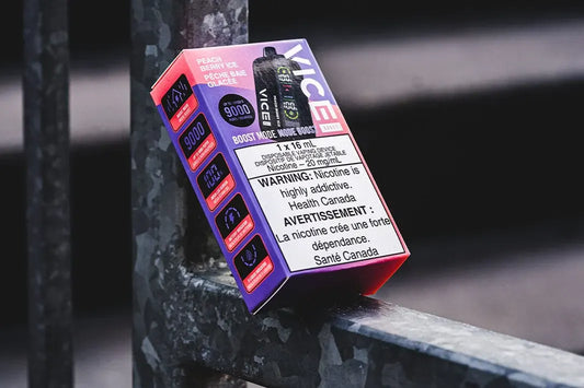 Vice Boost disposable vape box with nicotine warning label resting on a metal railing outdoors